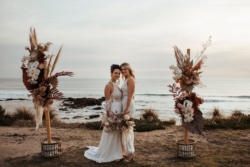 beachside wedding ceremony set up, same sex beach wedding, clifftop rust and peach flower ceremony setup